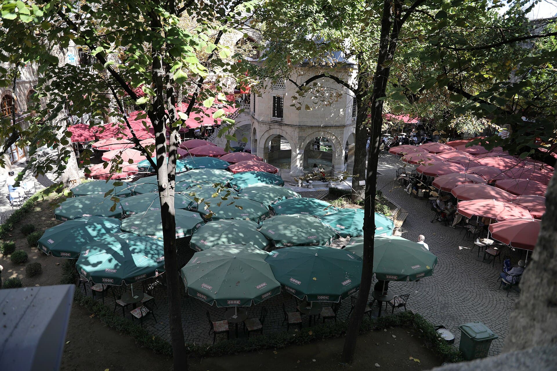 Koza Han courtyard with domed mosque, şadırvan fountain, and plane trees.