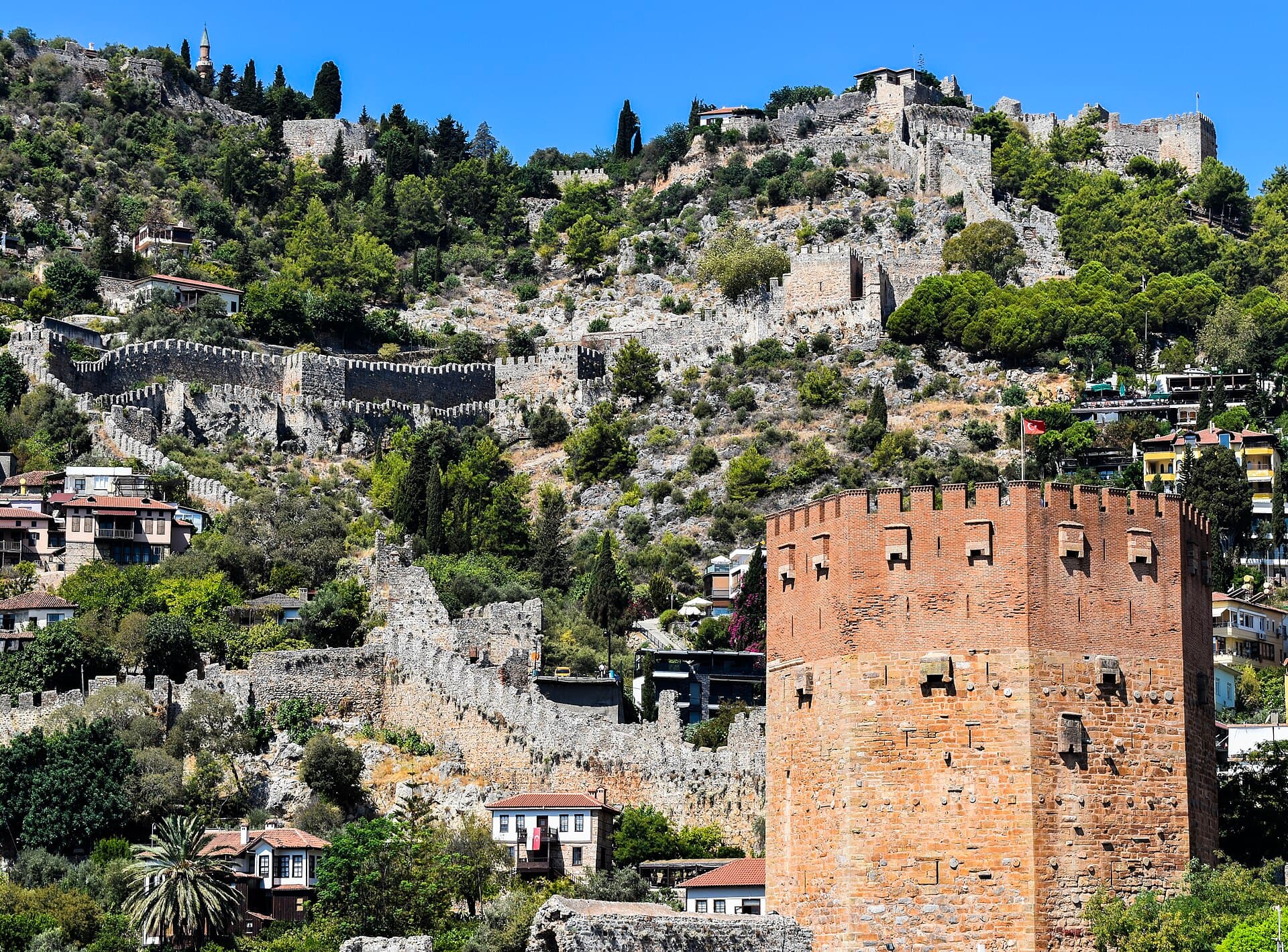 The octagonal red-brick Kızıl Kule (Red Tower) with Alanya Castle behind it.