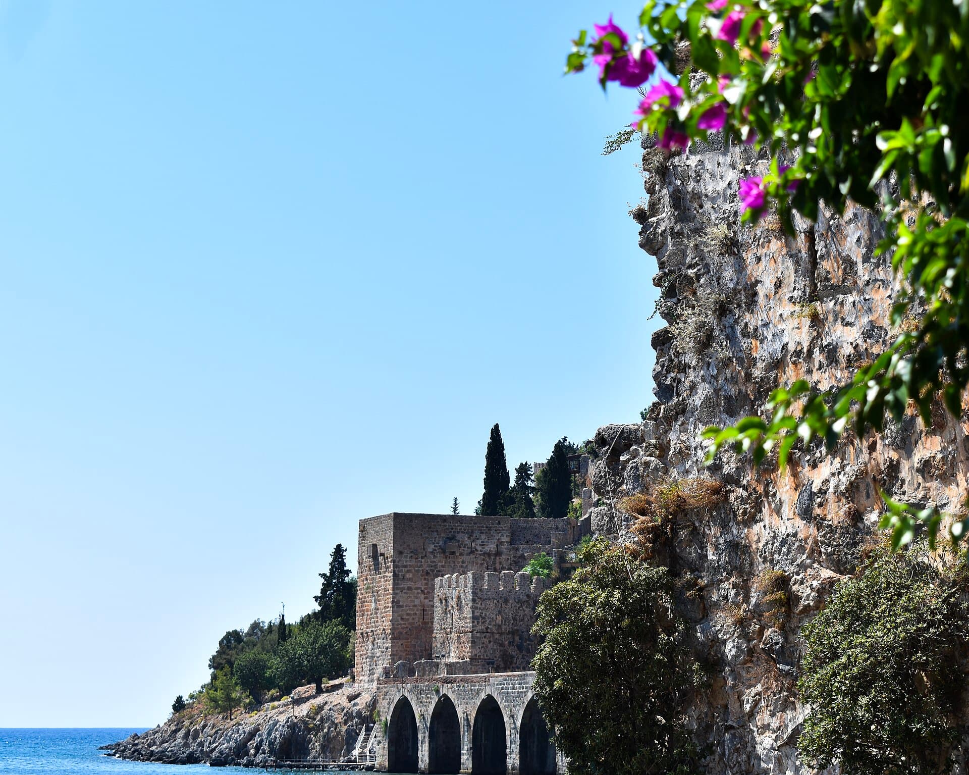 The vaulted arches of the Seljuk shipyard (Tersane) in Alanya, with greenery in the foreground.