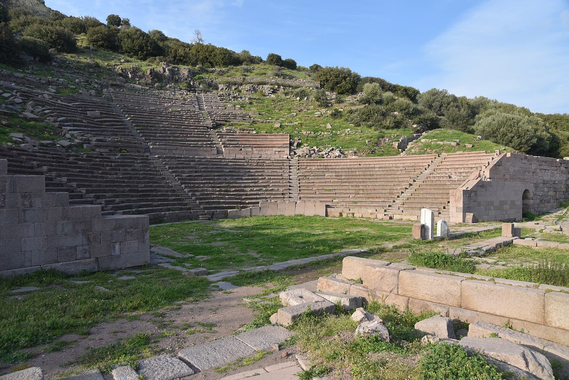 Frontal daylight view of the tiered stone seating of the Hellenistic theatre at Assos.