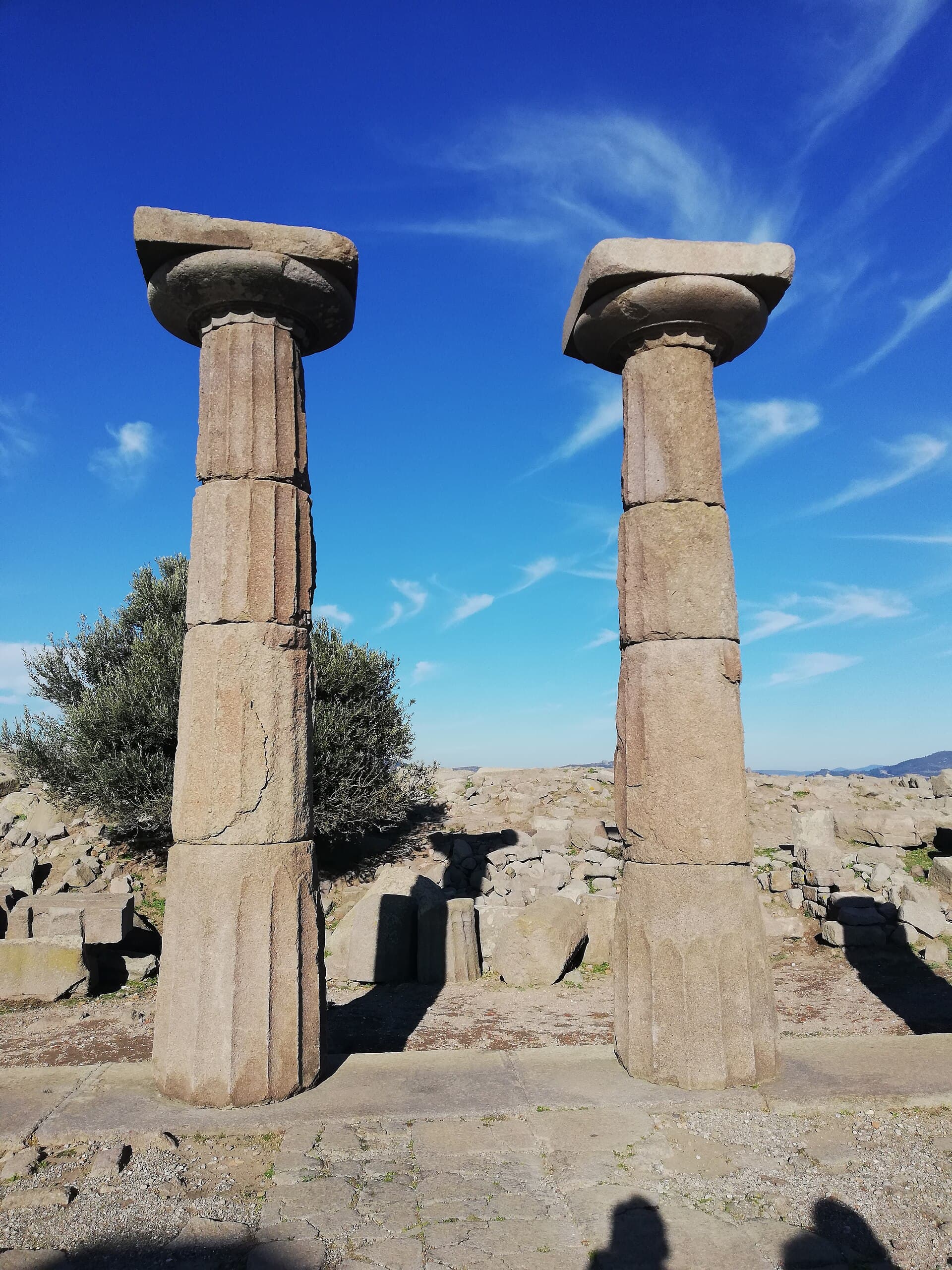 Standing restored Doric columns of the Temple of Athena at Assos against a blue sky.