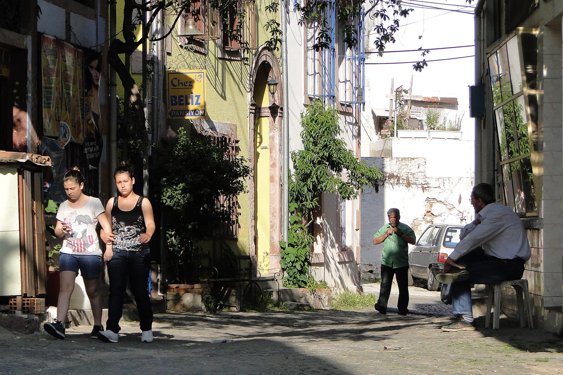 Daytime street scene among Ottoman-Greek stone houses in Ayvalık's old quarter.