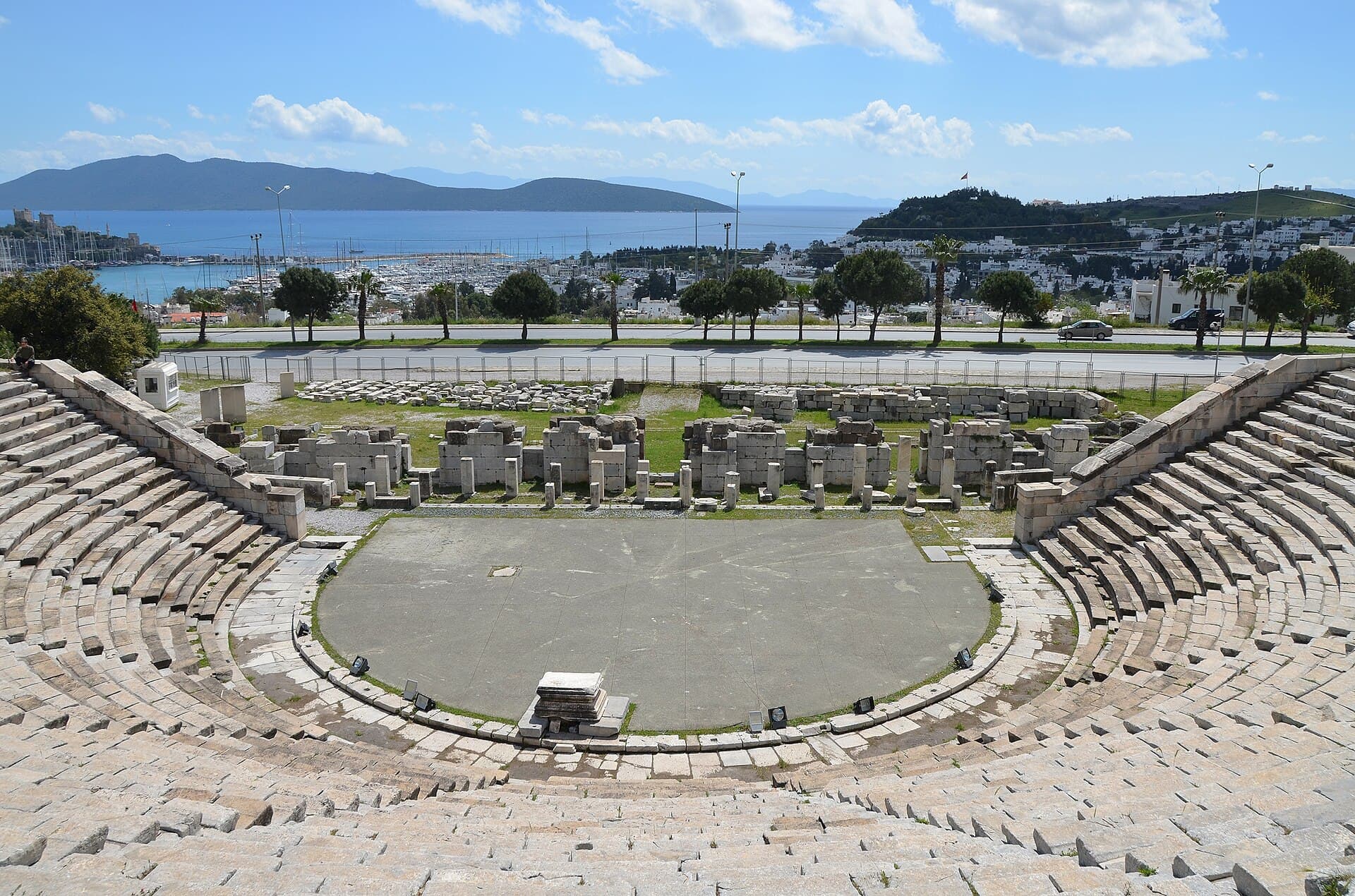 Wide view of the ancient theatre's curved stone seating bowl carved into the hillside.