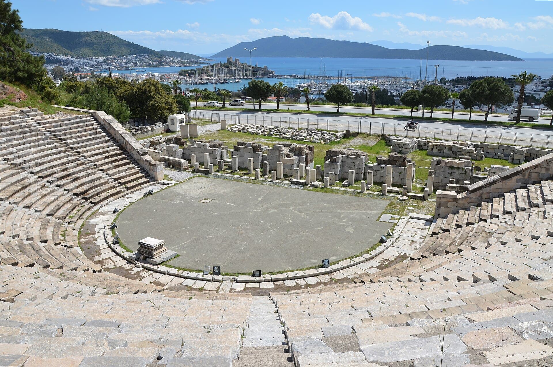 Theatre seating rows with the stage ruins and Bodrum's bay in the distance.