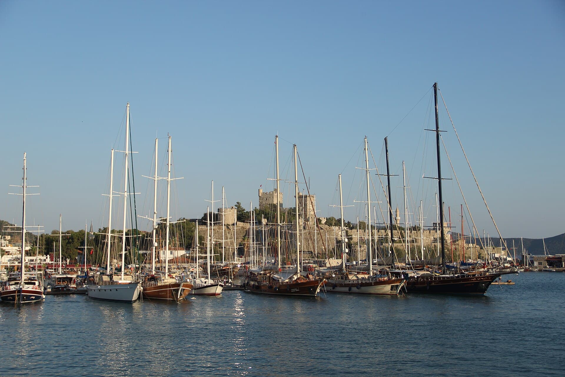 Wooden gulets moored along Bodrum's harbour with St. Peter's Castle behind.