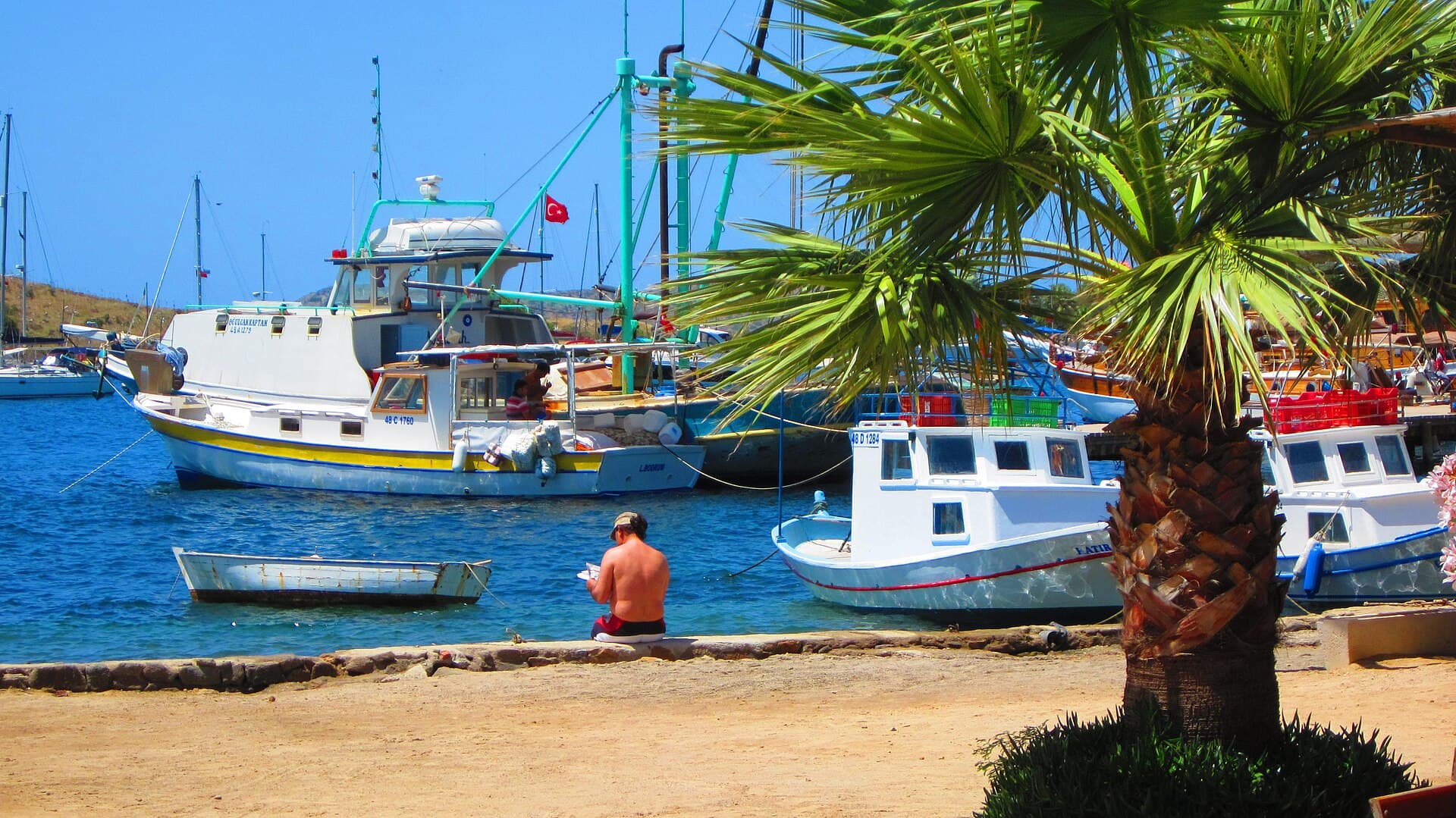 Clear turquoise bay water and boats along the Gümüşlük shoreline, Bodrum.