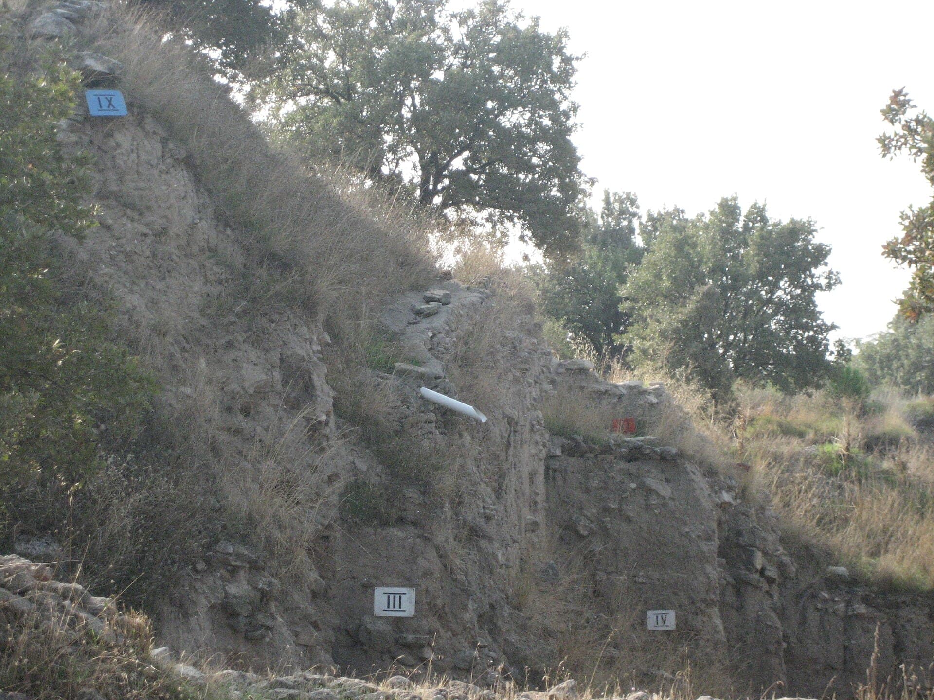 Close-up cross-section of Troy's mound wall showing labeled stratified city layers