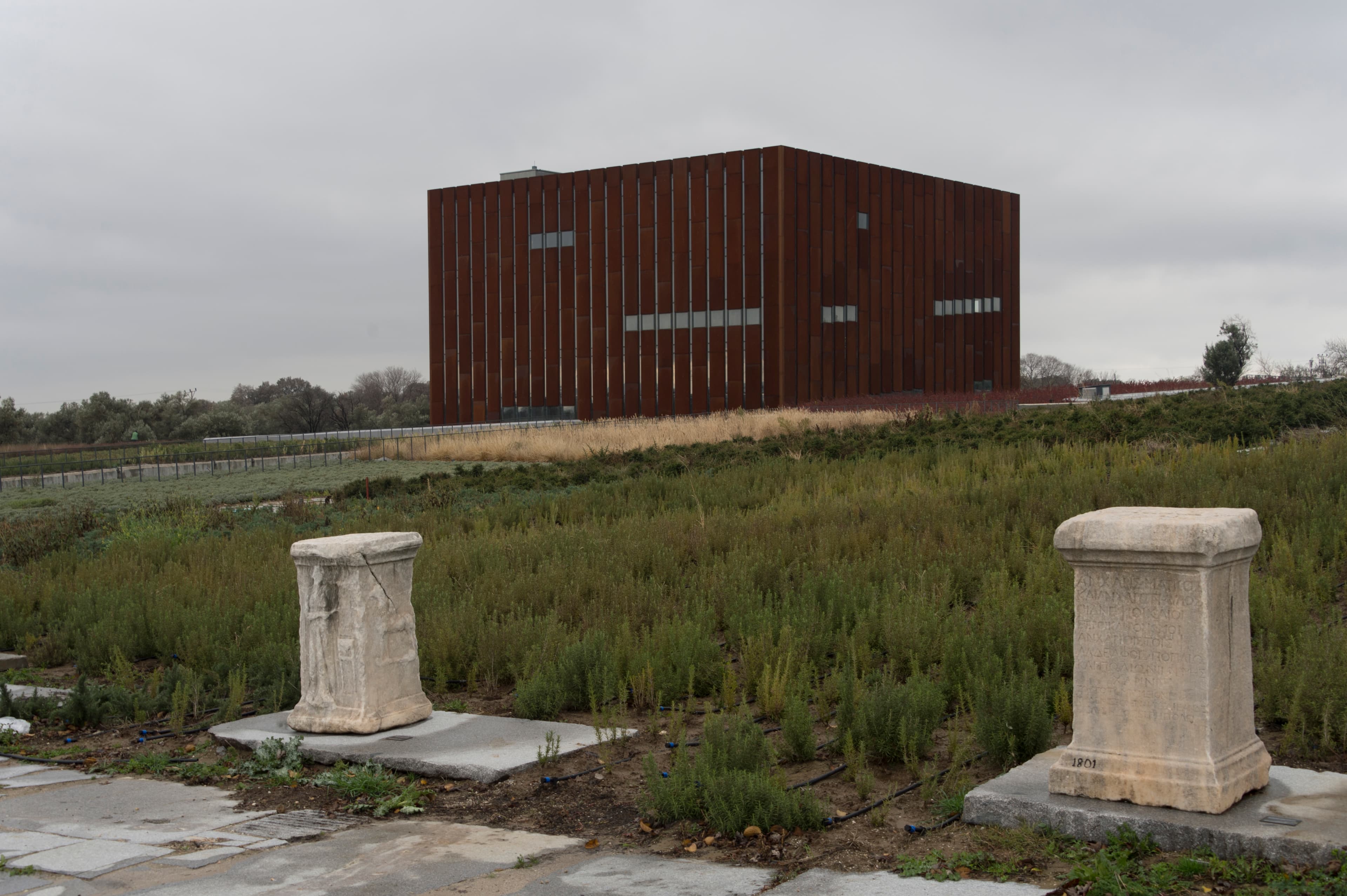 The Troy Museum's rusted Corten-steel cube rising above a wildflower meadow