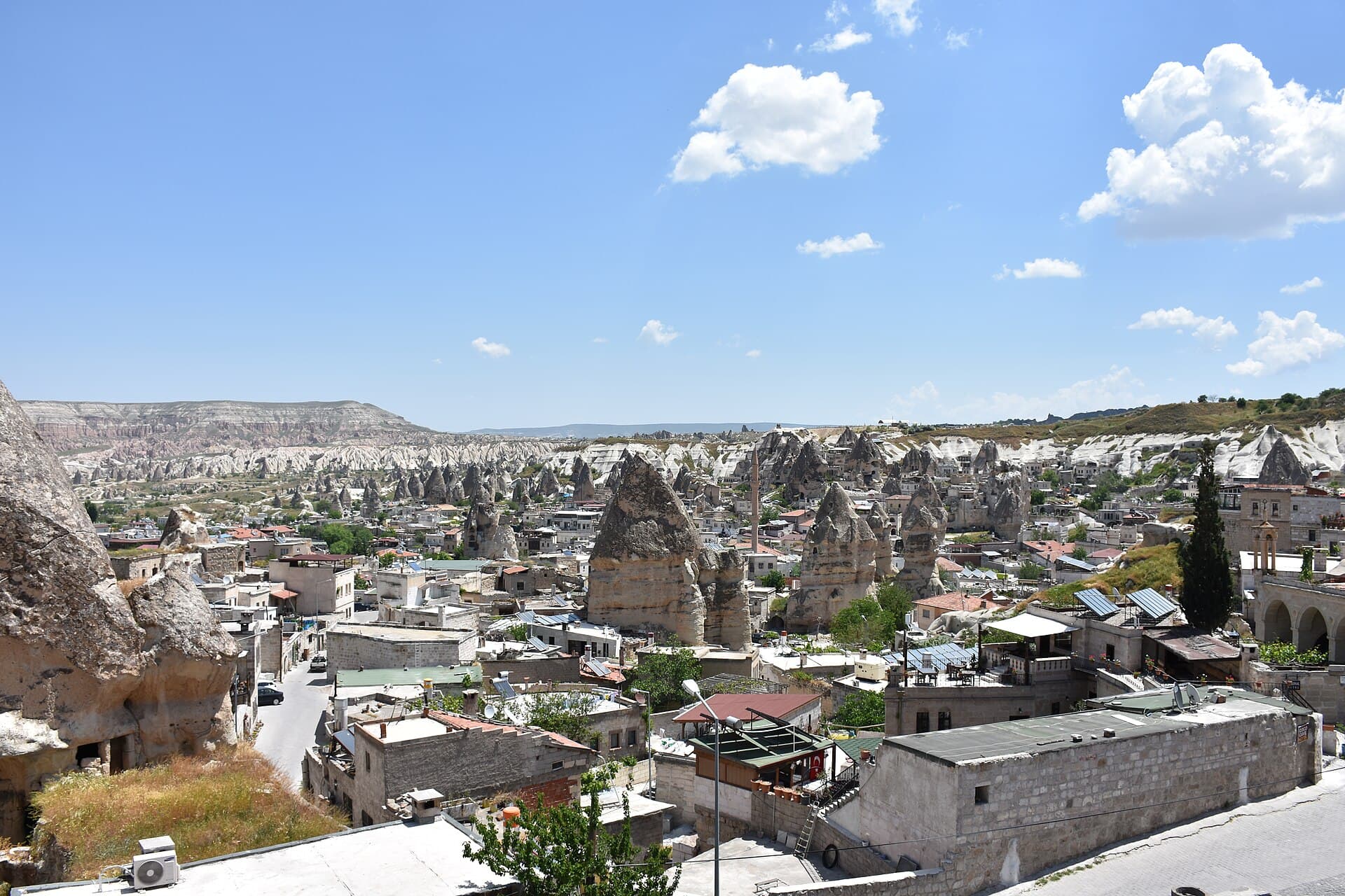 View over Göreme, where cone-shaped fairy chimney rock formations rise among stone houses and rooftops in the valley