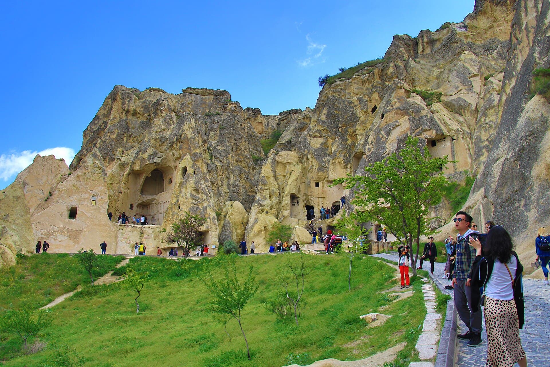 Rock-cut Byzantine chapels with carved facades and doorways set into the tuff cliffs of Göreme Open Air Museum, with visitors on the path below