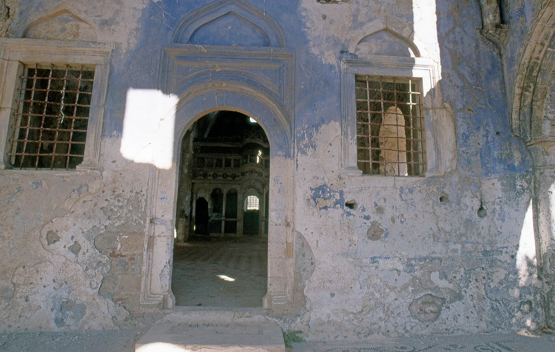 Weathered blue facade and arched doorway of Kayaköy's ruined Lower Church.