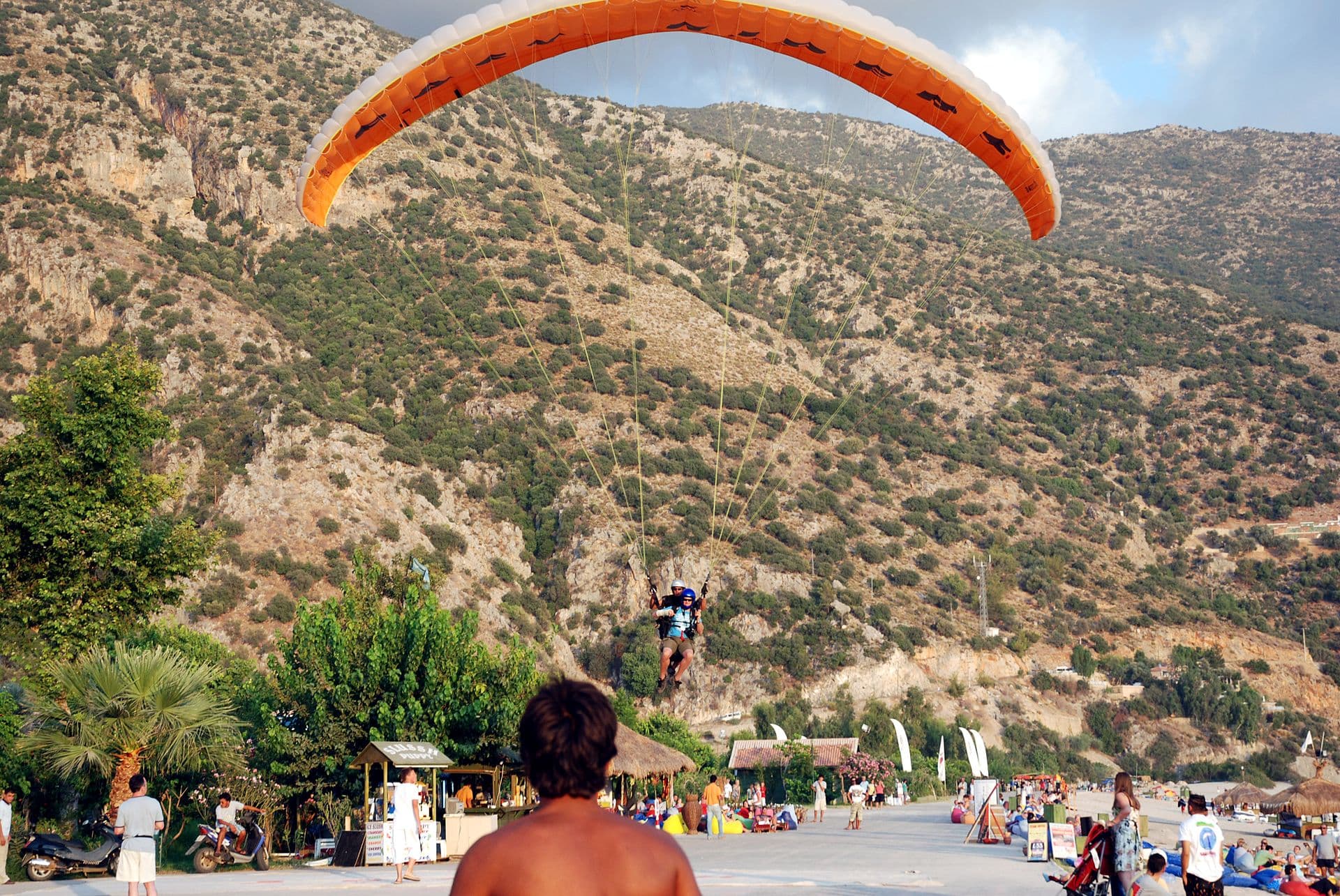 Tandem paraglider pilot and passenger land on Ölüdeniz's Belcekız Beach.