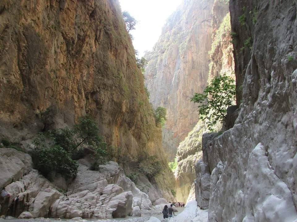 Hikers dwarfed by Saklıkent Gorge's sheer, narrow limestone canyon walls.