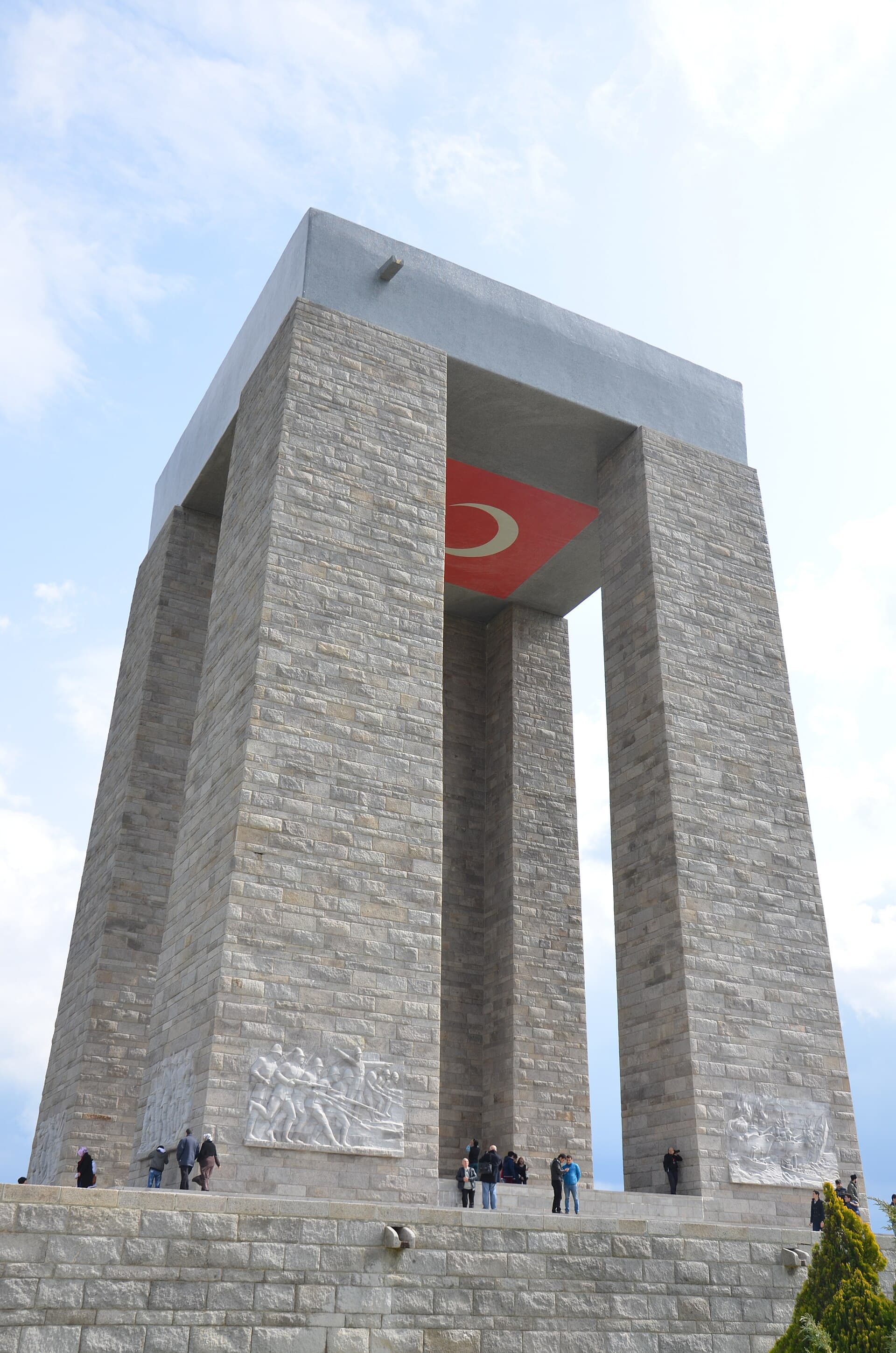 Upward view of the four concrete legs of Çanakkale Martyrs' Memorial with visitors below