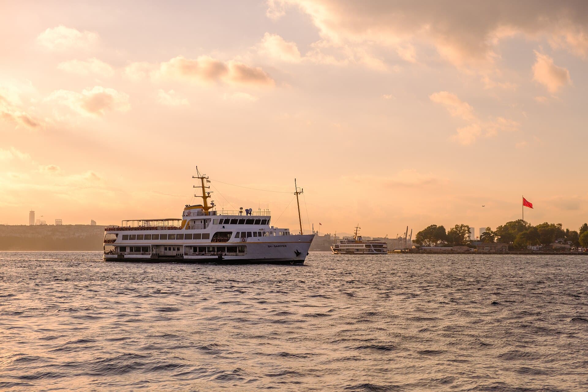 Şehir Hatları ferry ŞH-Sarıyer crossing the Bosphorus at sunset, with the Istanbul shoreline in the distance