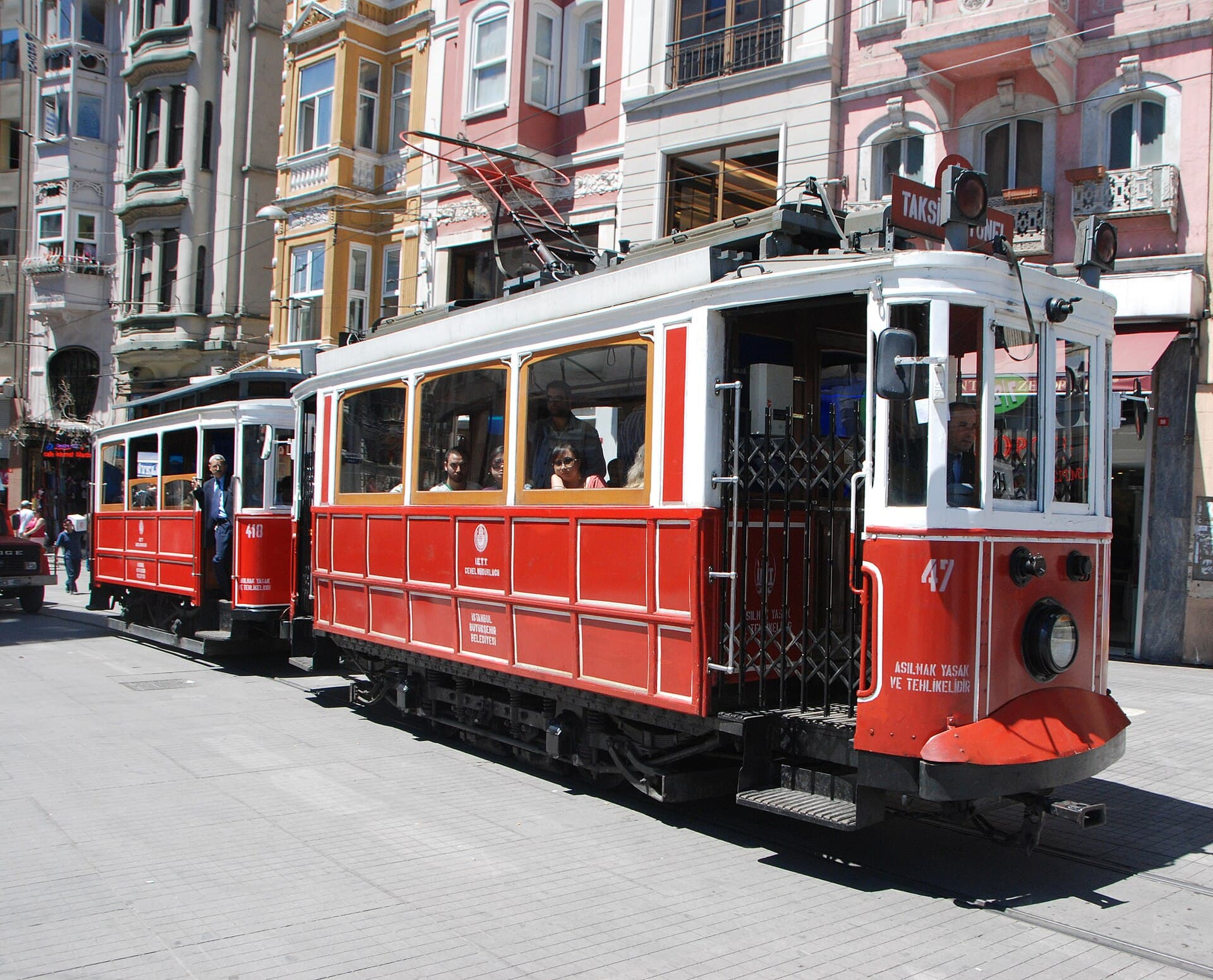 Two red heritage T2 trams stopped on İstiklal Avenue in Beyoğlu, with colourful historic façades lining the pedestrian street