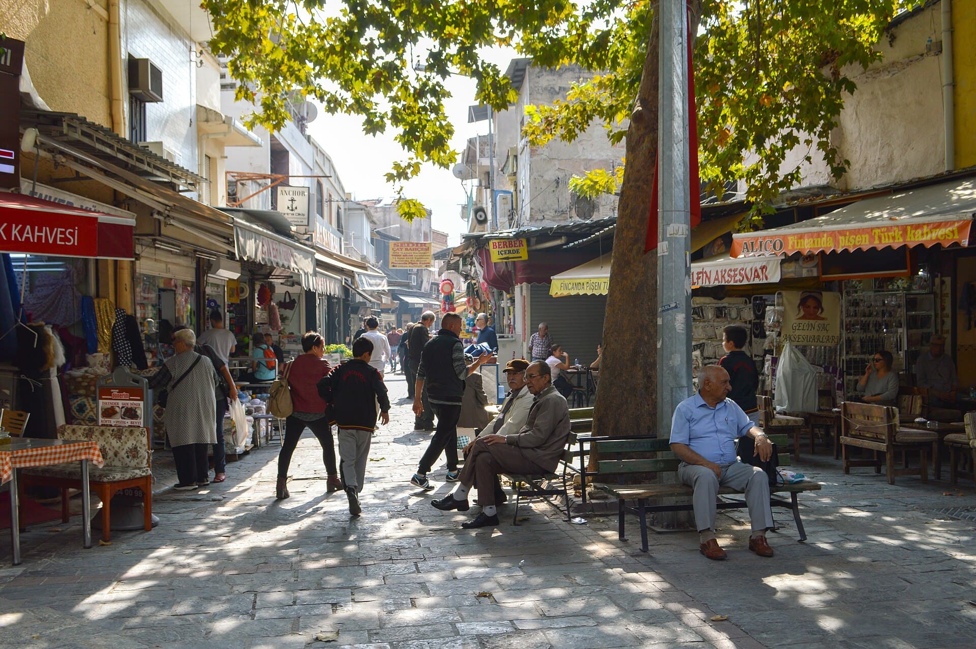 Sunlit market street in Kemeraltı Bazaar with pedestrians and storefronts, İzmir.