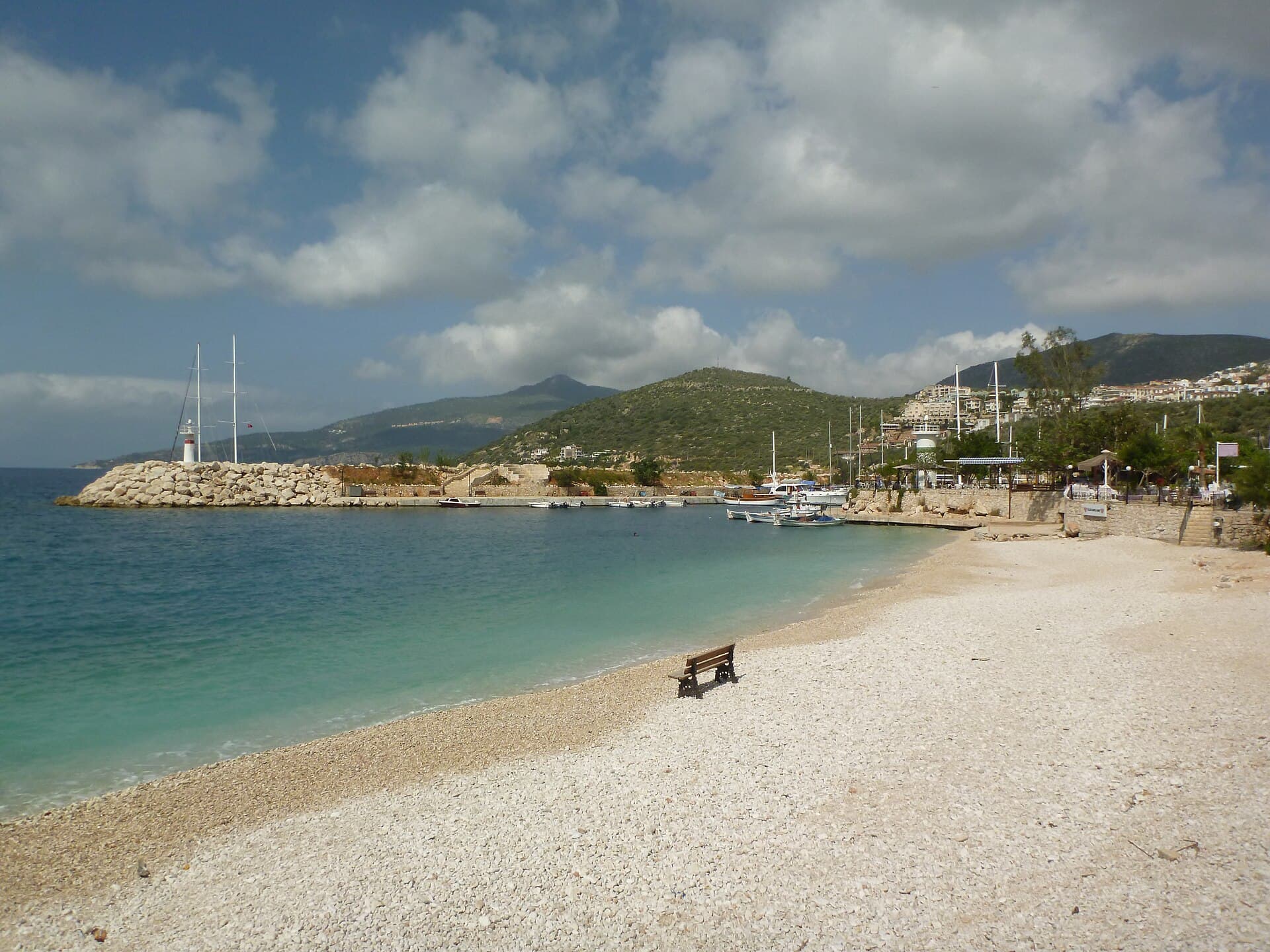 Boats moored in Kalkan's small harbour beside whitewashed waterfront buildings, Türkiye.