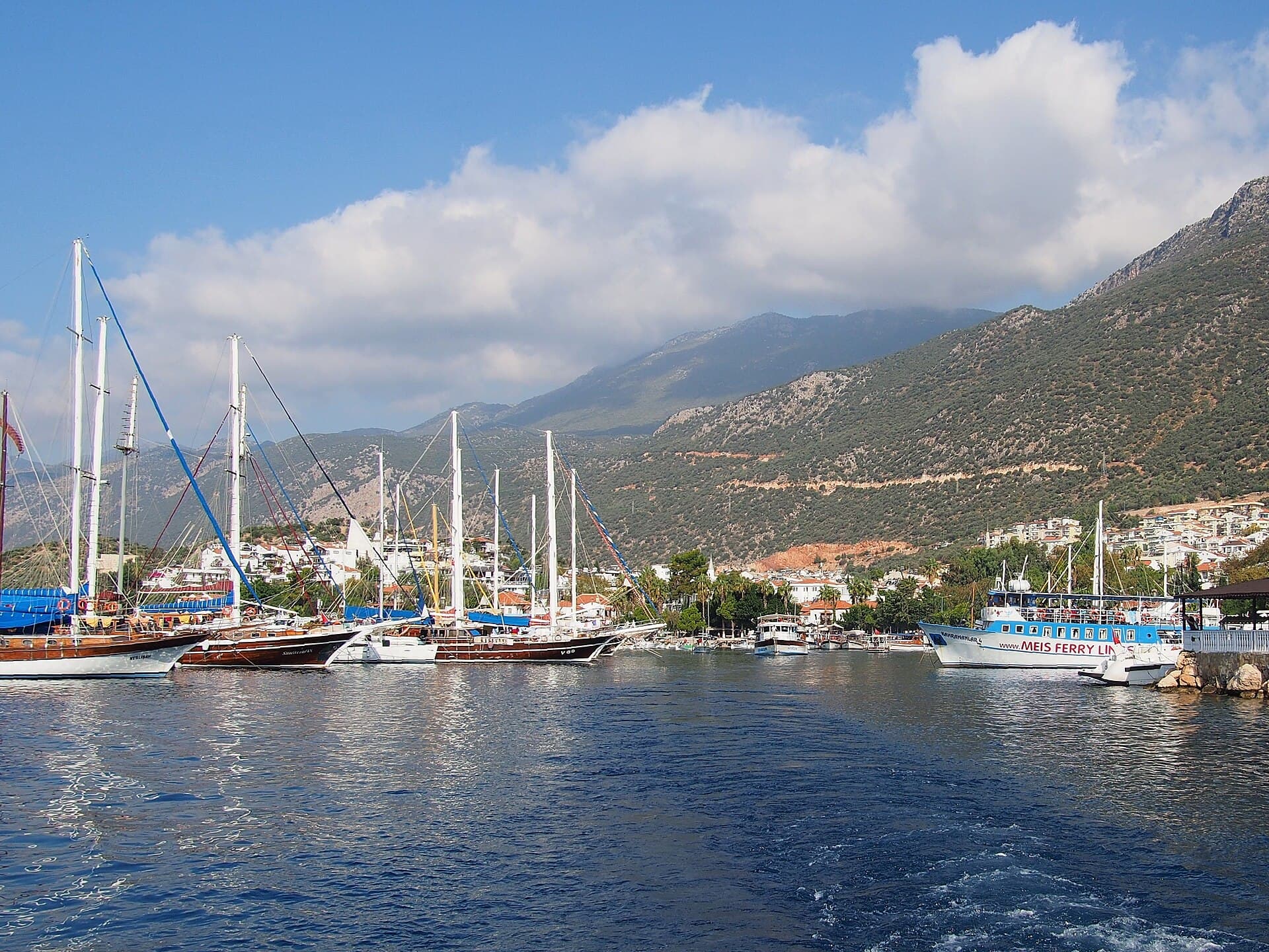 Boats moored in Kaş harbour beside whitewashed waterfront buildings, Türkiye.