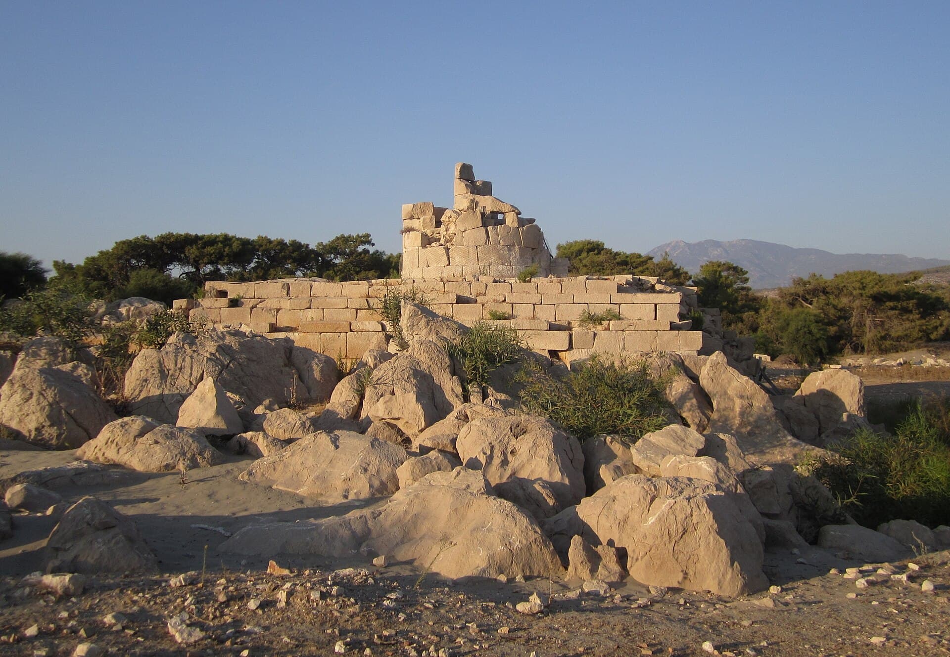 Weathered stone ruins of Patara's ancient Roman lighthouse near the sand dunes.