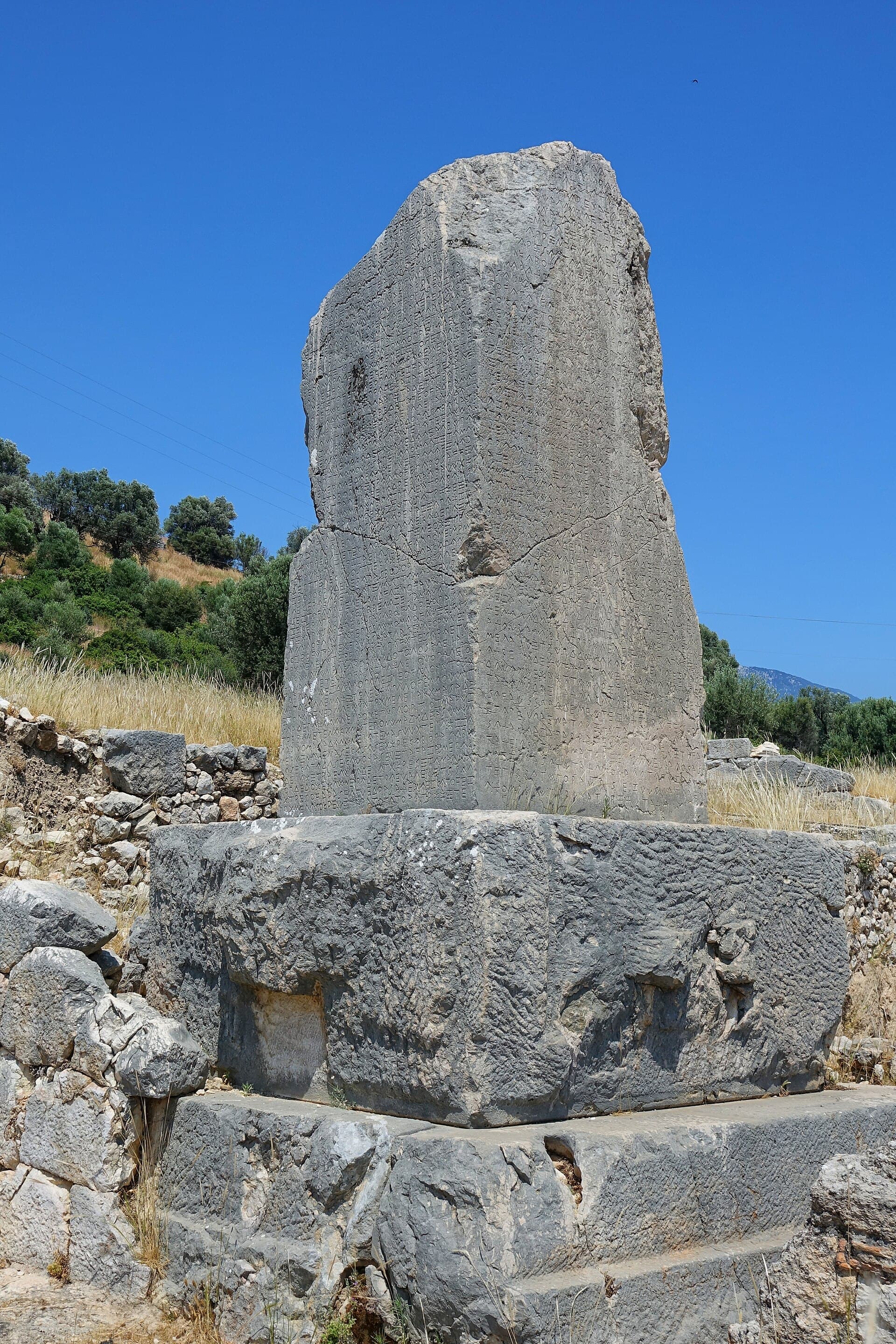 Tall carved Lycian pillar tomb inscribed with ancient text at Xanthos, Türkiye.