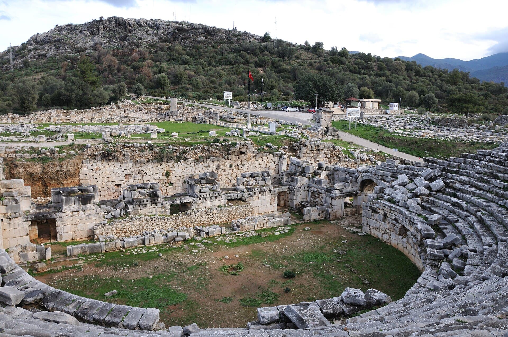 Sunlit stone seating rows of the Roman theatre overlooking Xanthos ruins, Türkiye.