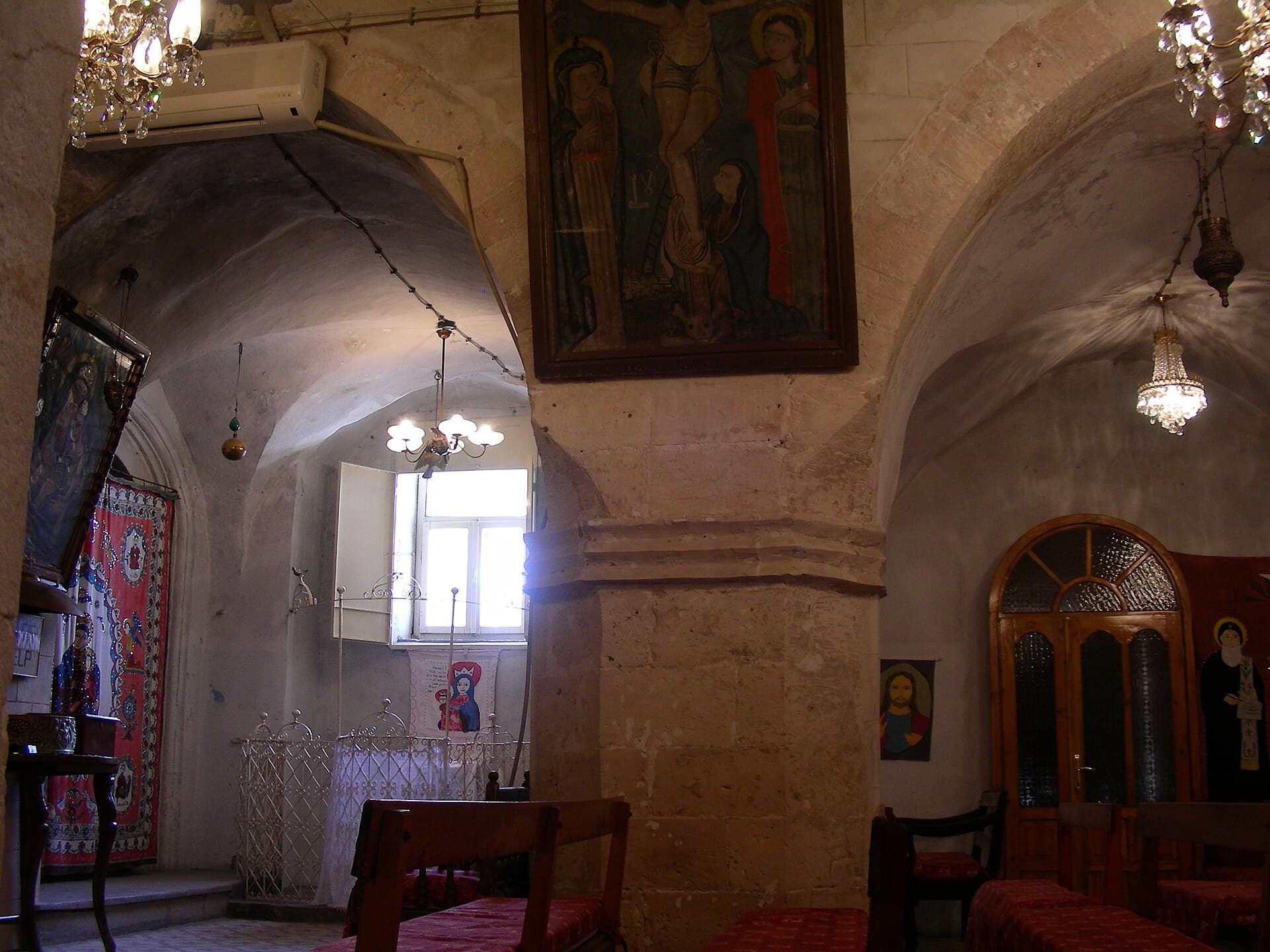 Interior of Kırklar Kilisesi in Mardin showing a stone pillar and arches.