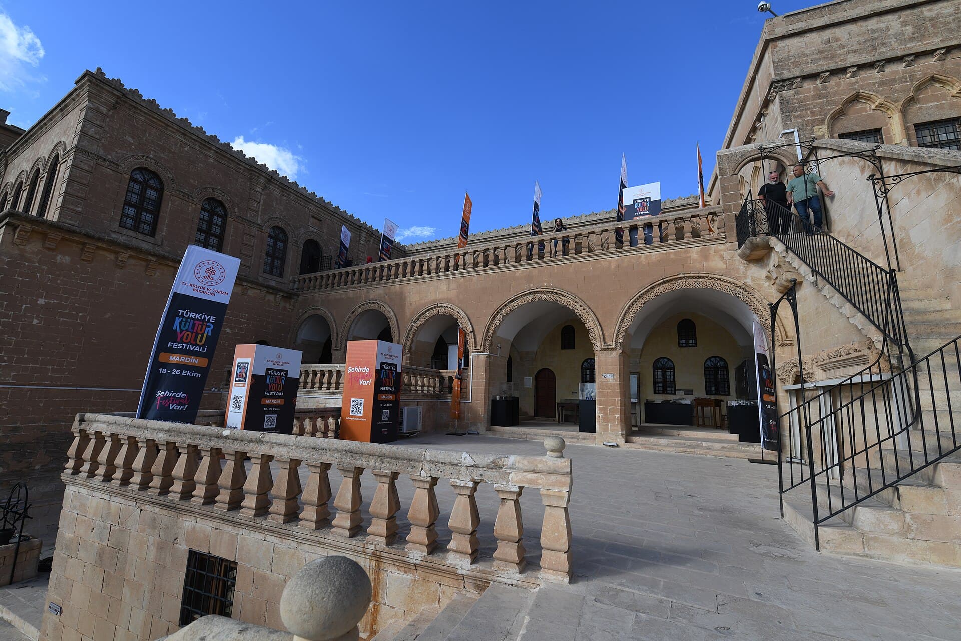 Sunlit courtyard of Mardin Museum showing carved stone arches and balustrade.