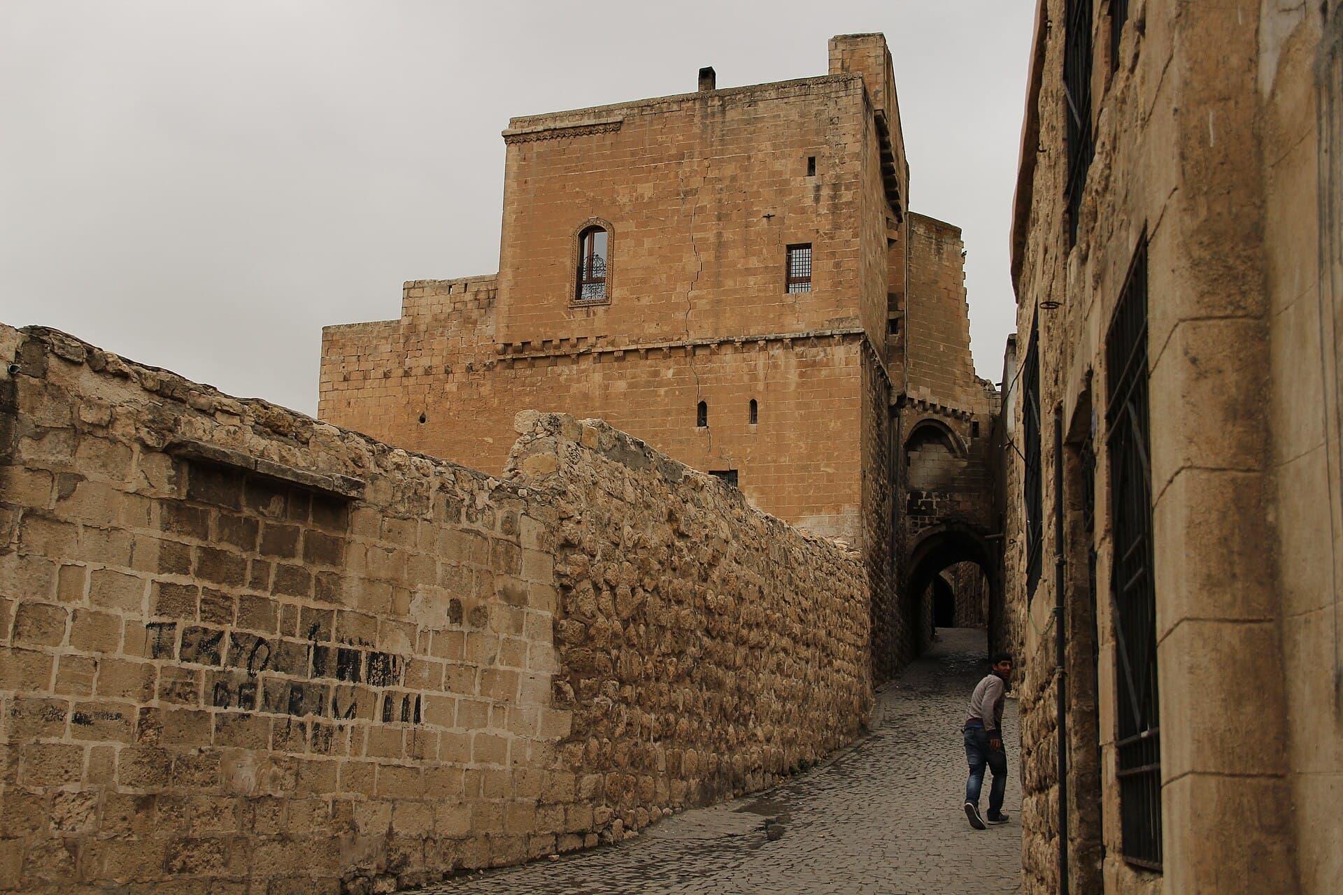 Narrow cobbled lane between honey-stone houses in Mardin's old city.