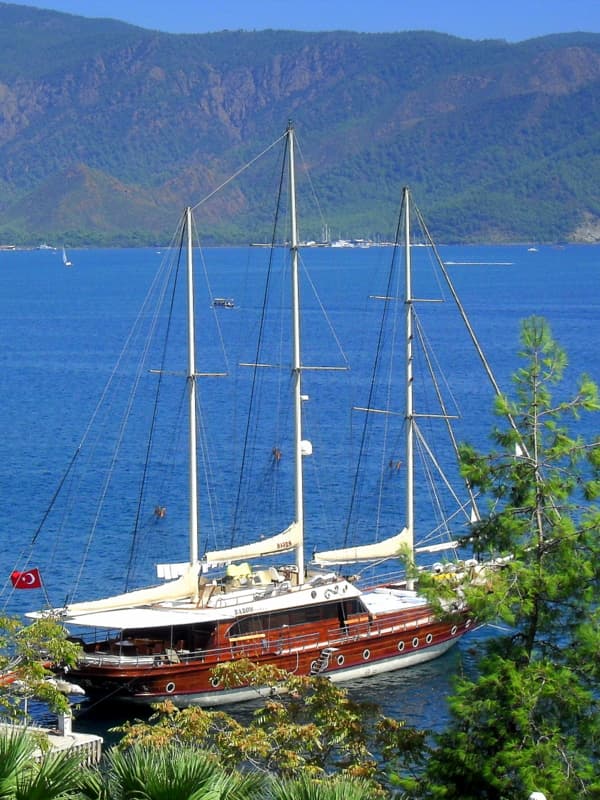 A wooden gulet sailing yacht anchored in a pine-fringed cove near Marmaris.