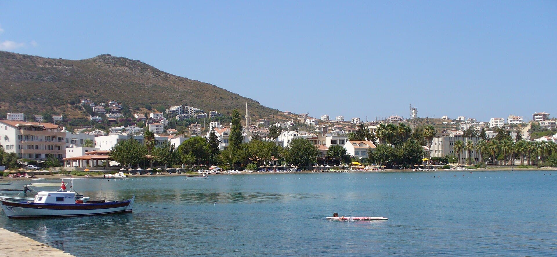 Wide panorama of Datça town, beach, and hillside from across the bay.