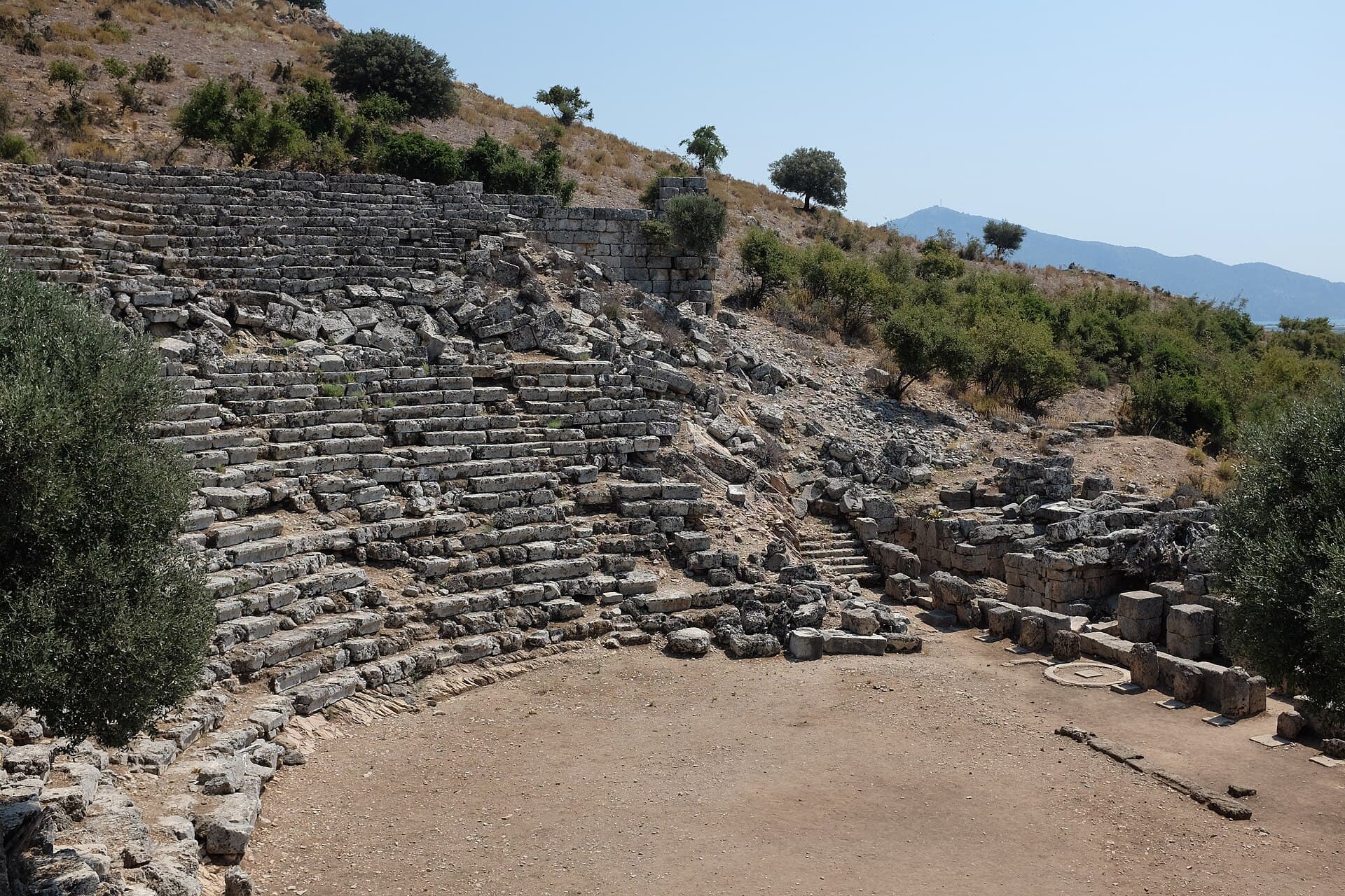 Collapsed stone seating rows of the ancient Kaunos theatre ruins.