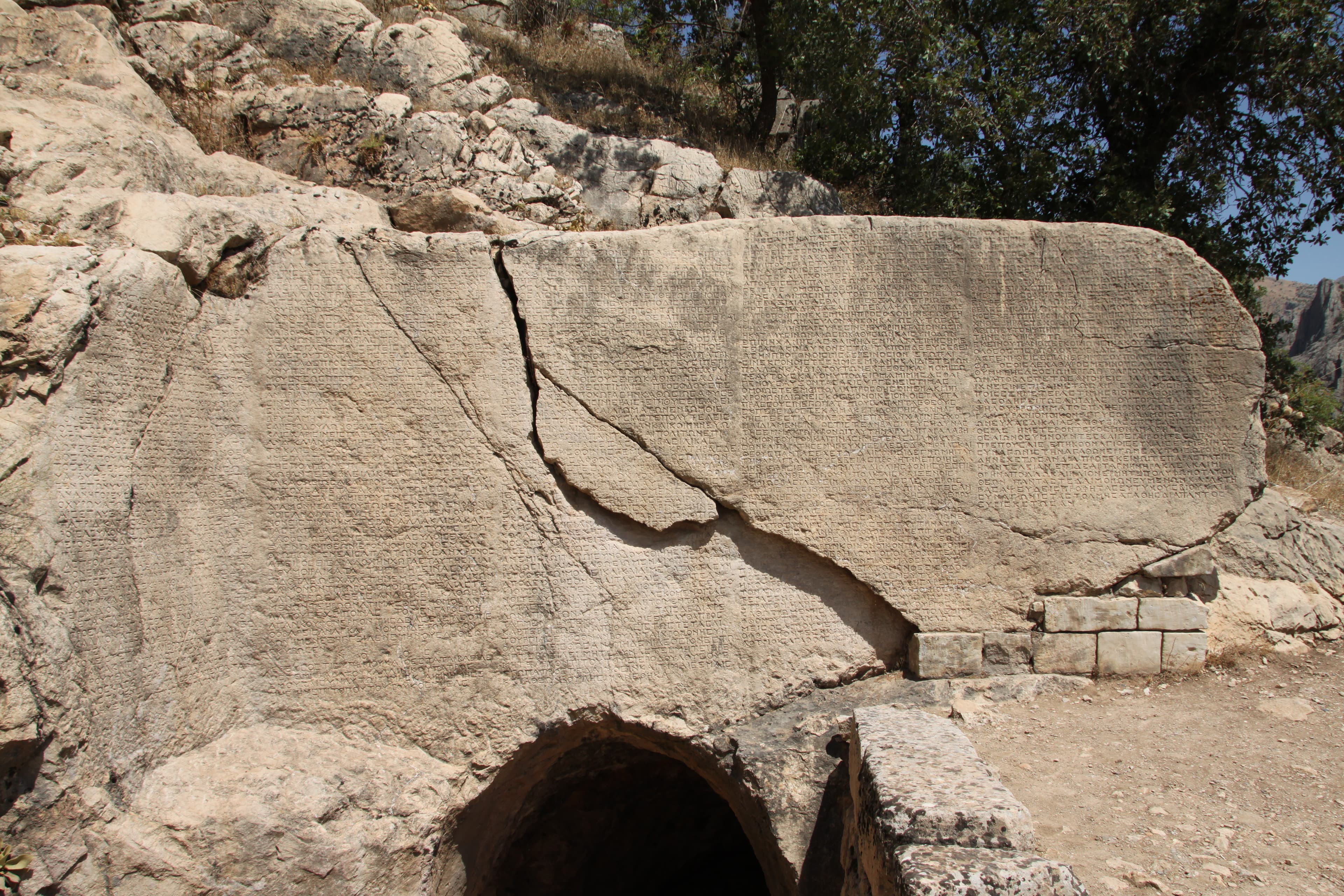Massive ancient Greek inscription carved into rock at Arsameia, tunnel entrance below