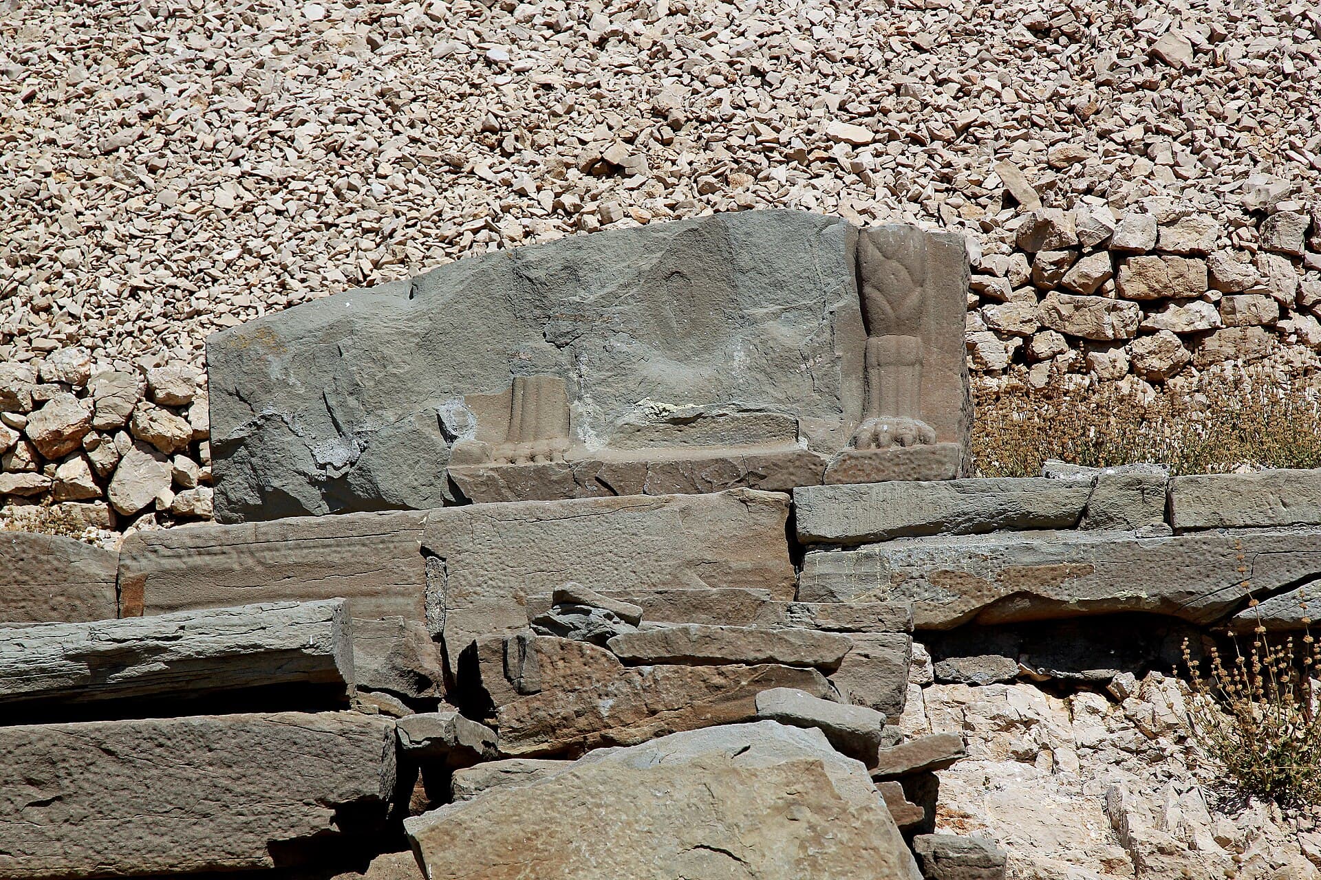 Weathered stone fragment of the Zeus dexiosis relief base on the West Terrace