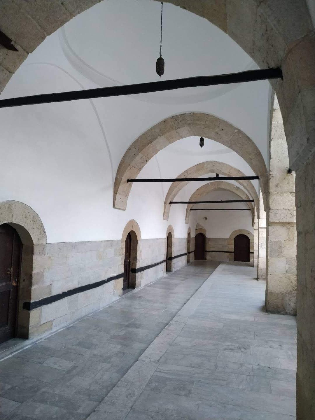 Stone barrel-vaulted arcade with arched doorways inside Cinci Han caravanserai.