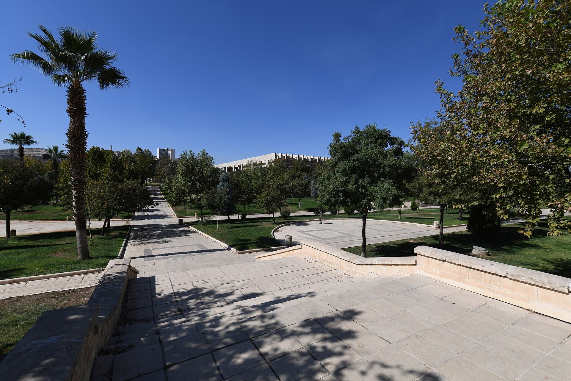 Şanlıurfa Archaeology Museum building exterior in a sunlit park setting.