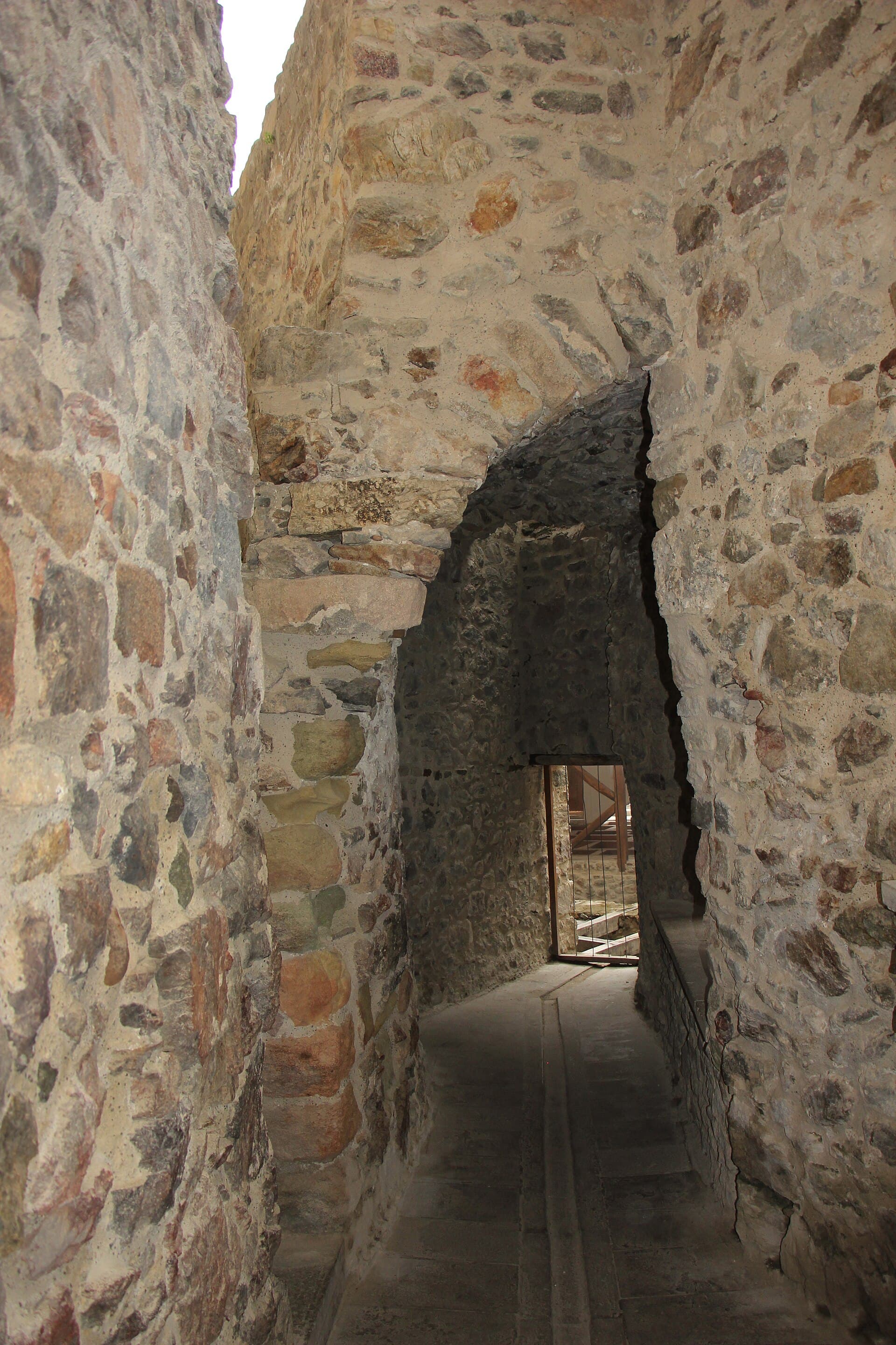 Narrow vaulted stone corridor with an arched doorway at Sümela Monastery